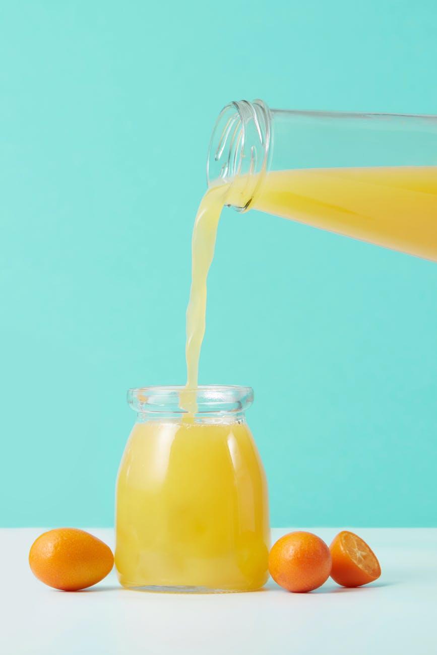 orange liquid pouring in clear glass jar