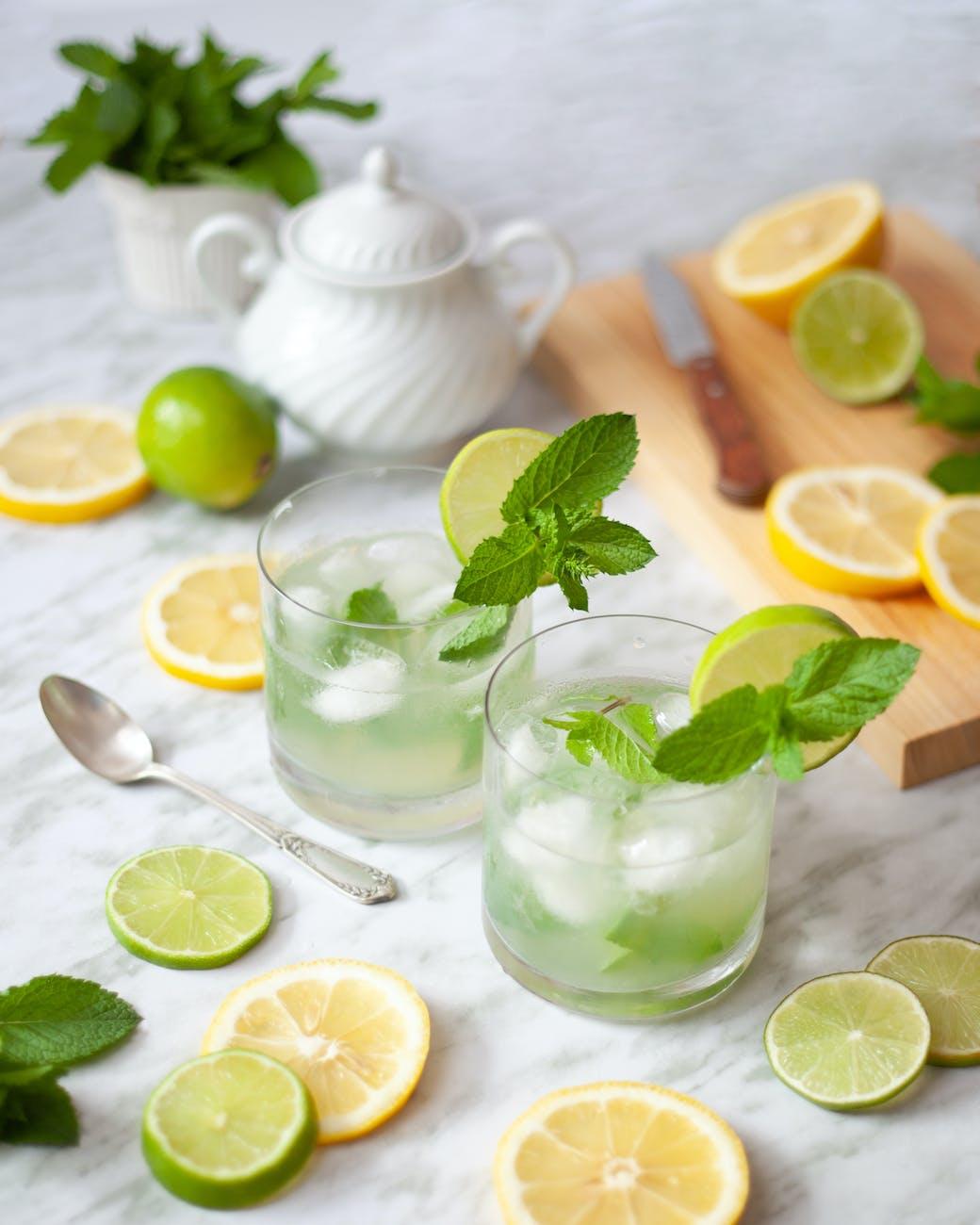 refreshing lemonade on table decorated with lemon and lime slices Photo by Chiaroscuro on Pexels.com