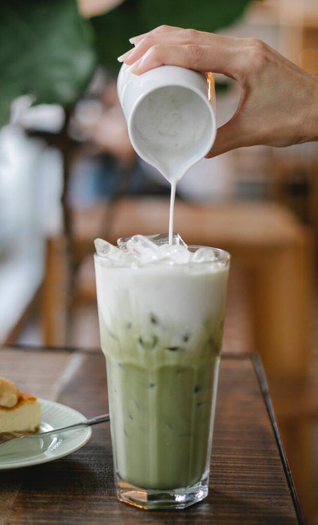 photo of of person pouring milk on matcha latte bubble tea