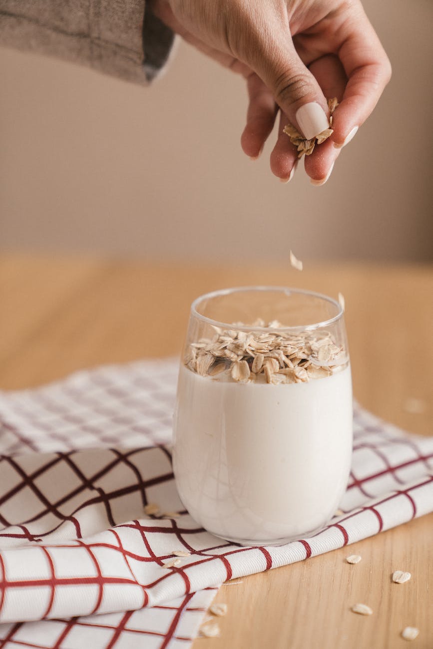 person sprinkling oats in a glass of smoothie Photo by Mike Jones on Pexels.com